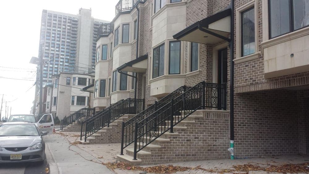 New townhouse complex with brick facade and iron railings, located on a city street.