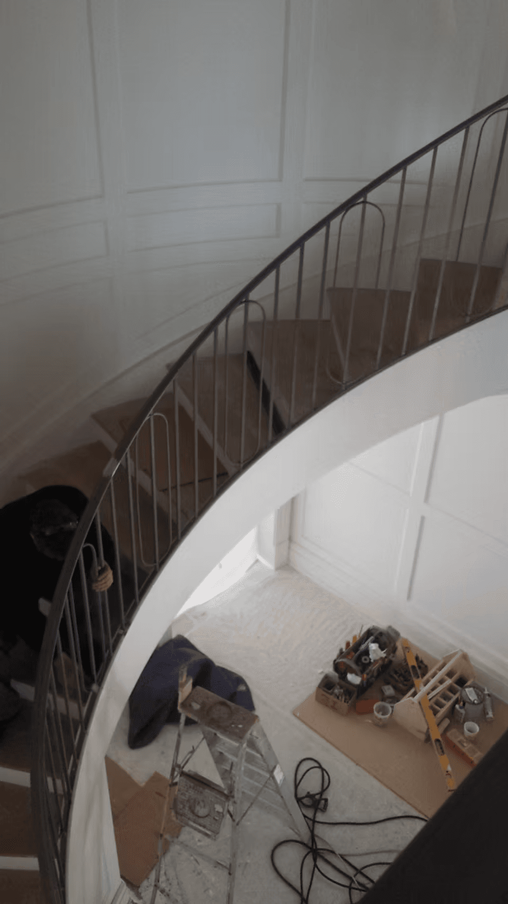 Curved staircase under renovation with tools and materials on the floor.