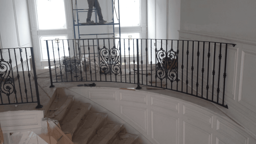 Elegant wrought iron railing on a curved staircase in a chic interior under construction.
