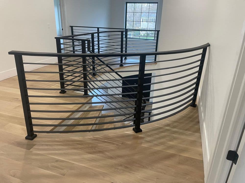 Modern staircase railing design in a bright, spacious interior with wooden floors.