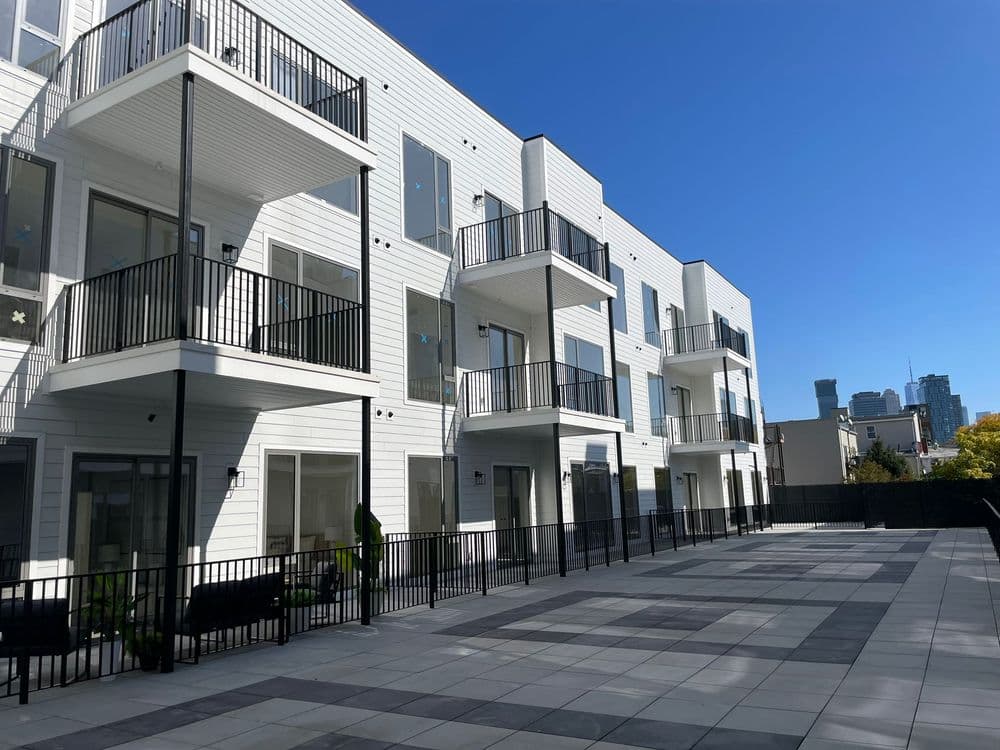 Modern apartment building with balconies and a spacious outdoor patio in an urban setting.