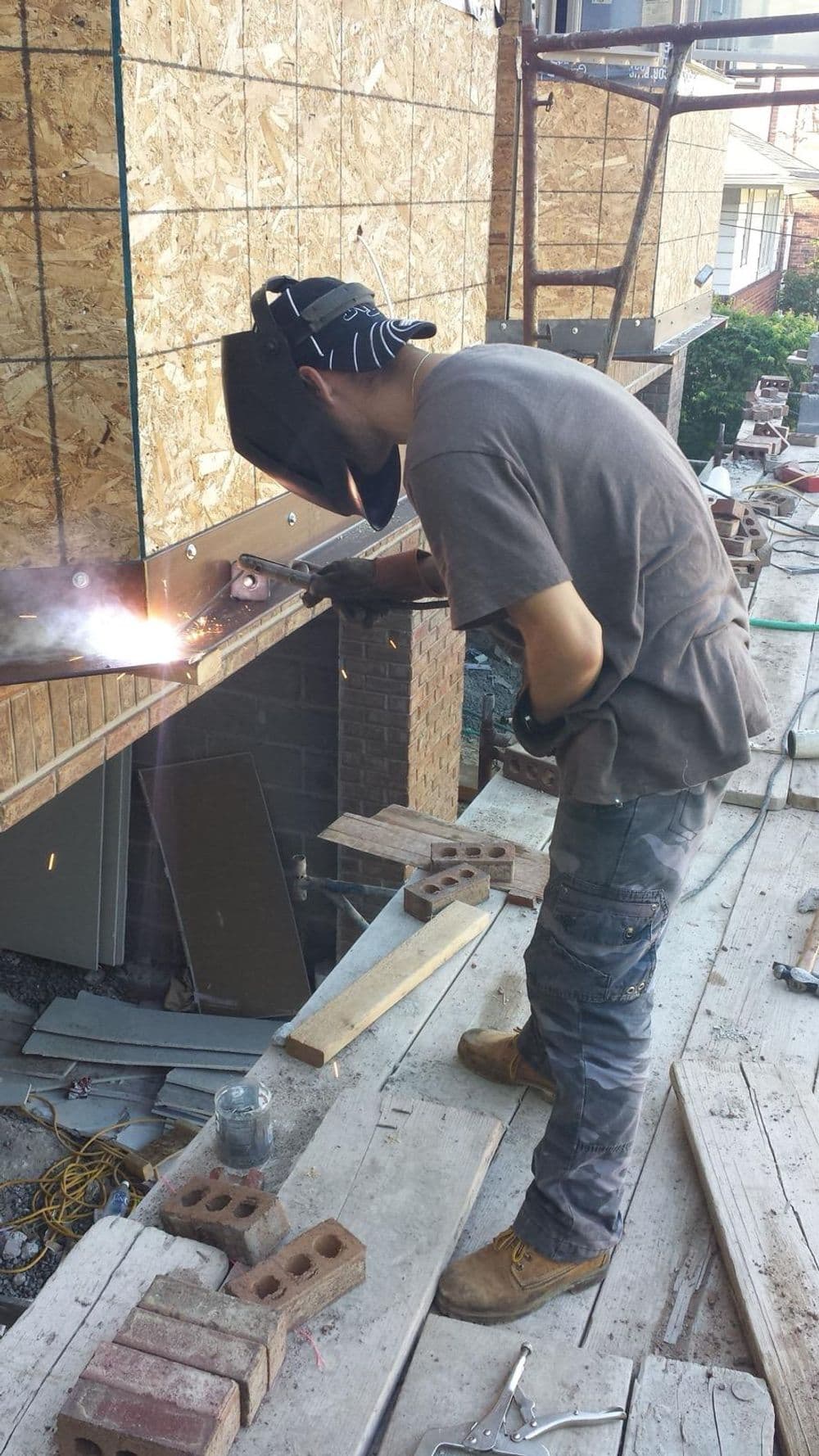 Welder working on a construction site, sparks flying, wearing protective gear.