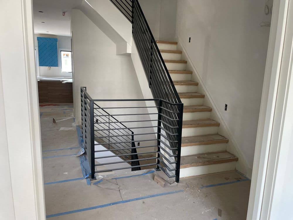 Modern interior view of a staircase with metal railing in a partially finished home.