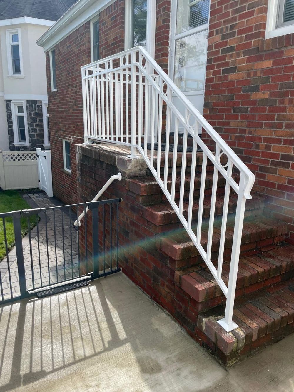White railing on brick steps leading to a home, enhancing safety and accessibility.