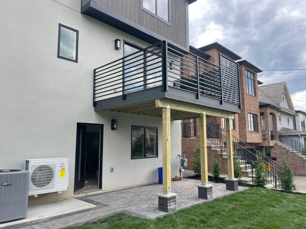 Modern house exterior featuring a raised balcony and air conditioning unit in a residential area.