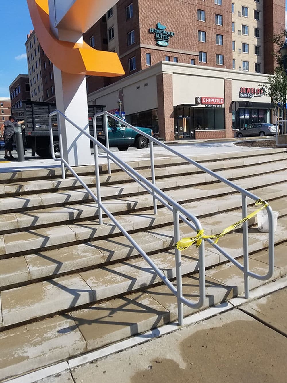 Accessibility ramp with caution tape at a building entrance, surrounded by urban scenery.