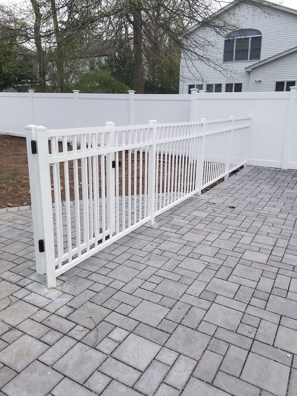 White vinyl fence installed on a paved patio, enhancing outdoor privacy and security.