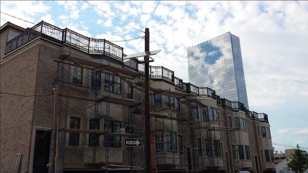 Newly constructed residential building with scaffolding and a modern skyscraper in the background.
