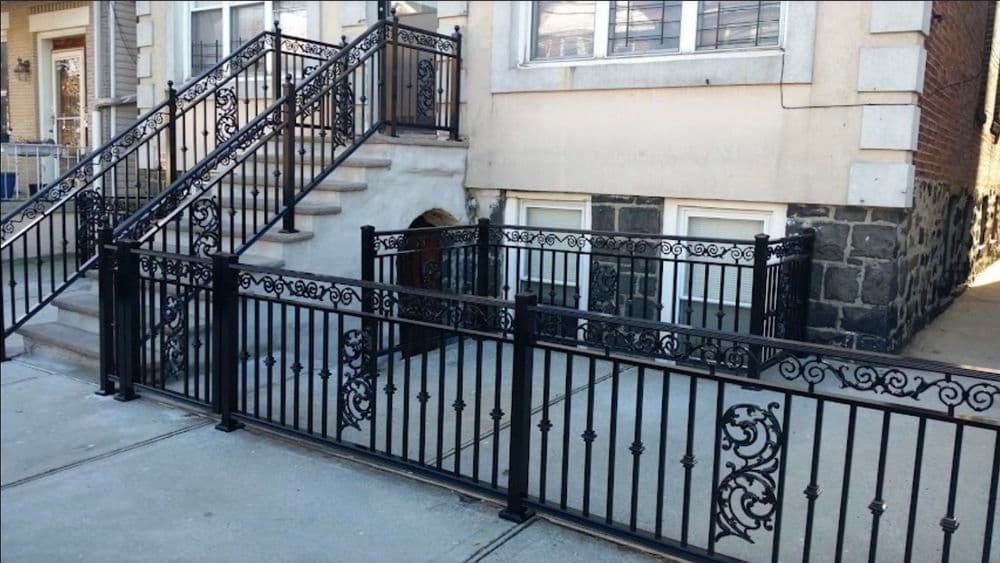Wrought iron fence and decorative railing with steps leading to a residential building.