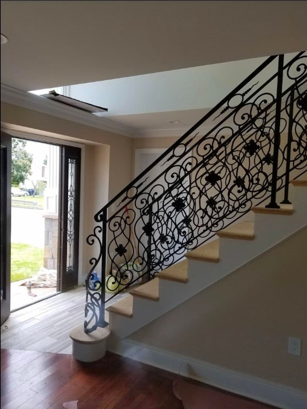 Indoor staircase with elegant wrought iron railing and hardwood flooring, bright natural light.