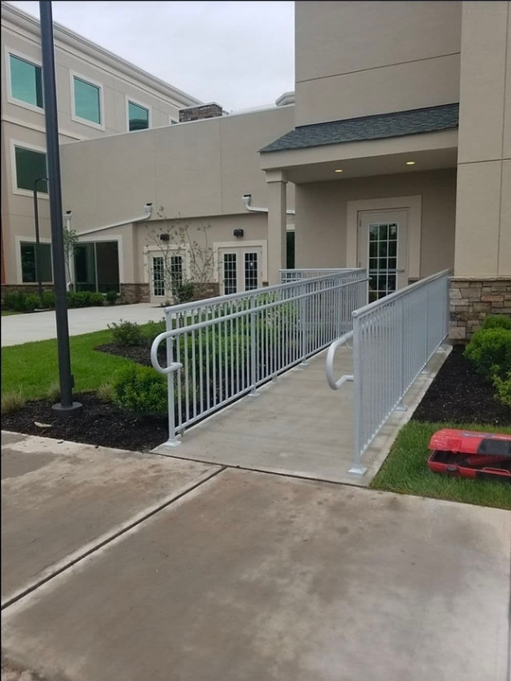 Accessibility ramp leading to a building entrance, featuring sturdy railings and concrete pathway.