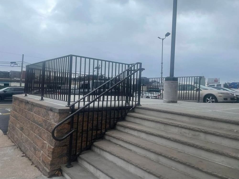 Accessible ramp leads to a raised platform near a parking lot, with cloudy skies above.