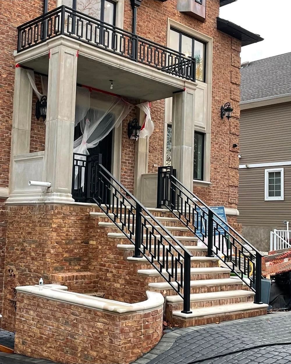 Modern brick house entrance with decorative railings and steps, showcasing architectural detail.