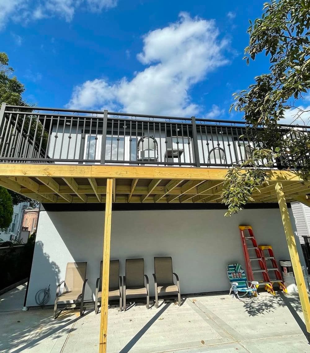 Modern elevated deck with comfortable chairs and bright blue sky background.