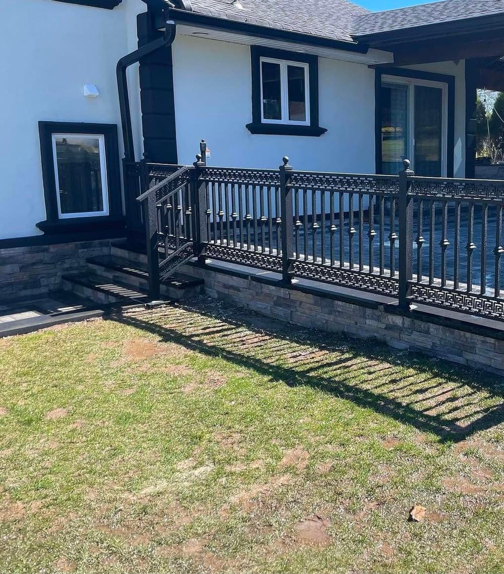 Modern home exterior with a black railing and stone accents on a sunny day.