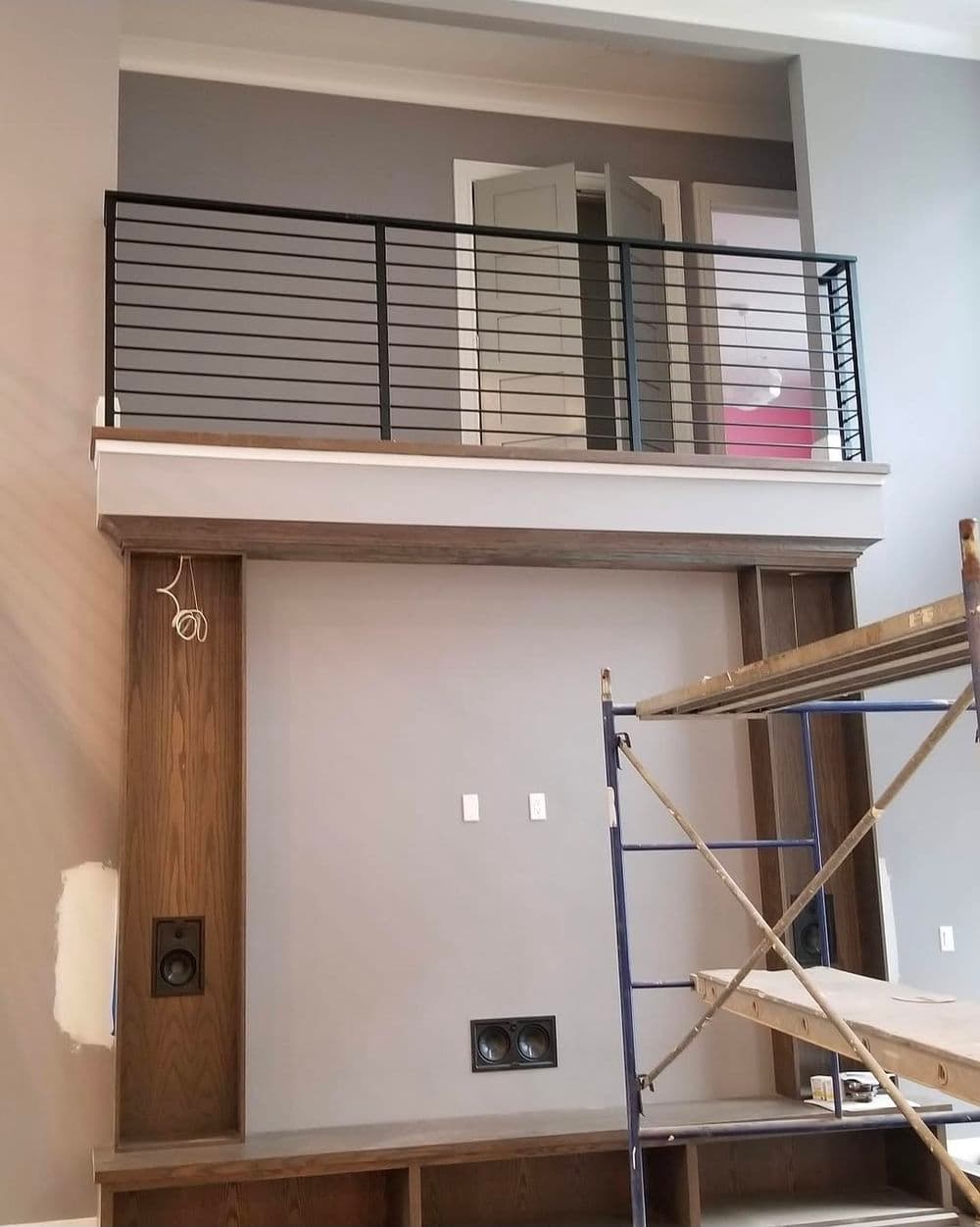 Modern interior featuring a two-story living room with a railing and construction scaffolding.