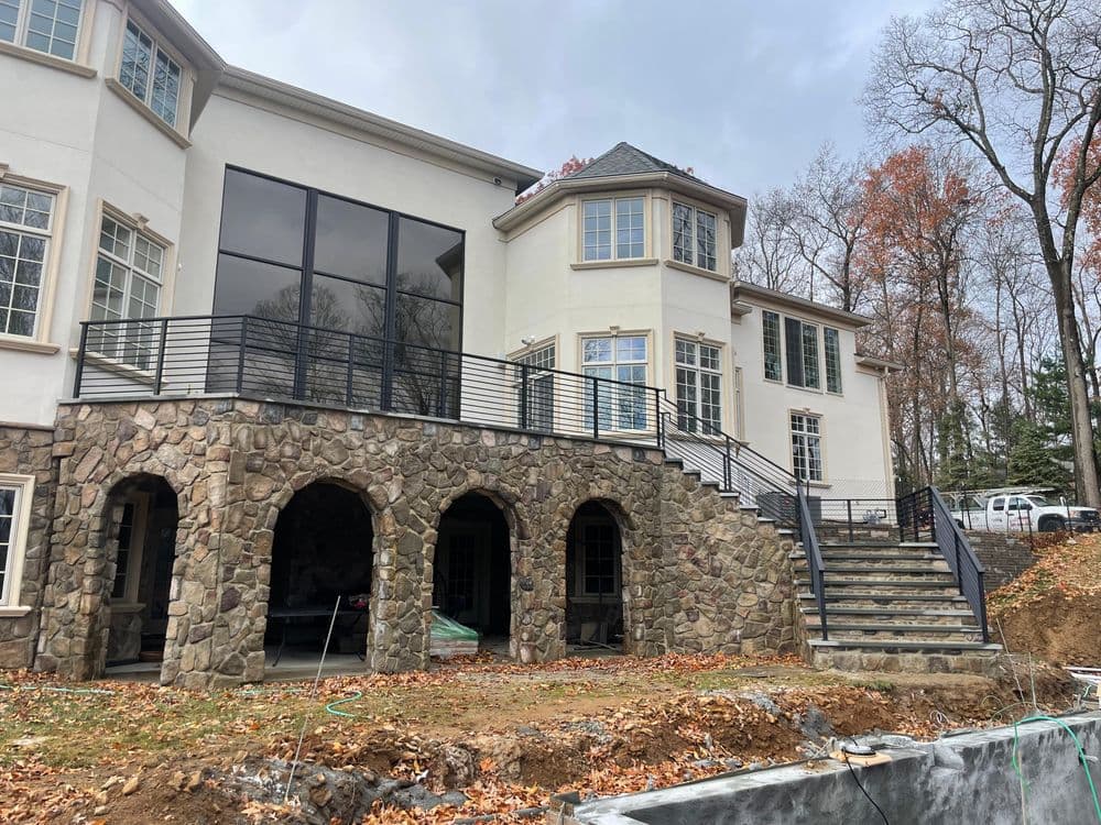 Luxury home with stone architecture and large windows, surrounded by autumn foliage.