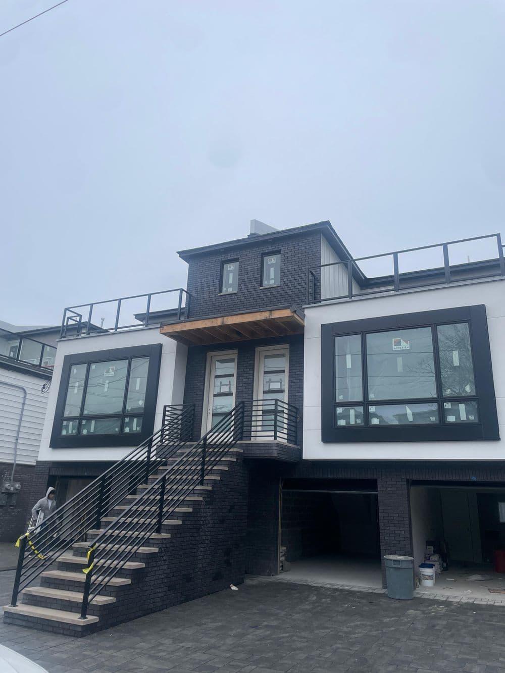 Modern two-story house with large windows, black exterior, and spacious front staircase.