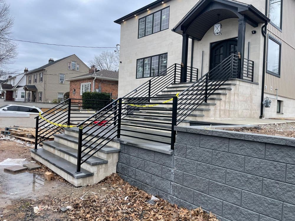 Modern outdoor staircase with black railings and yellow caution tape in front of a newly built home.