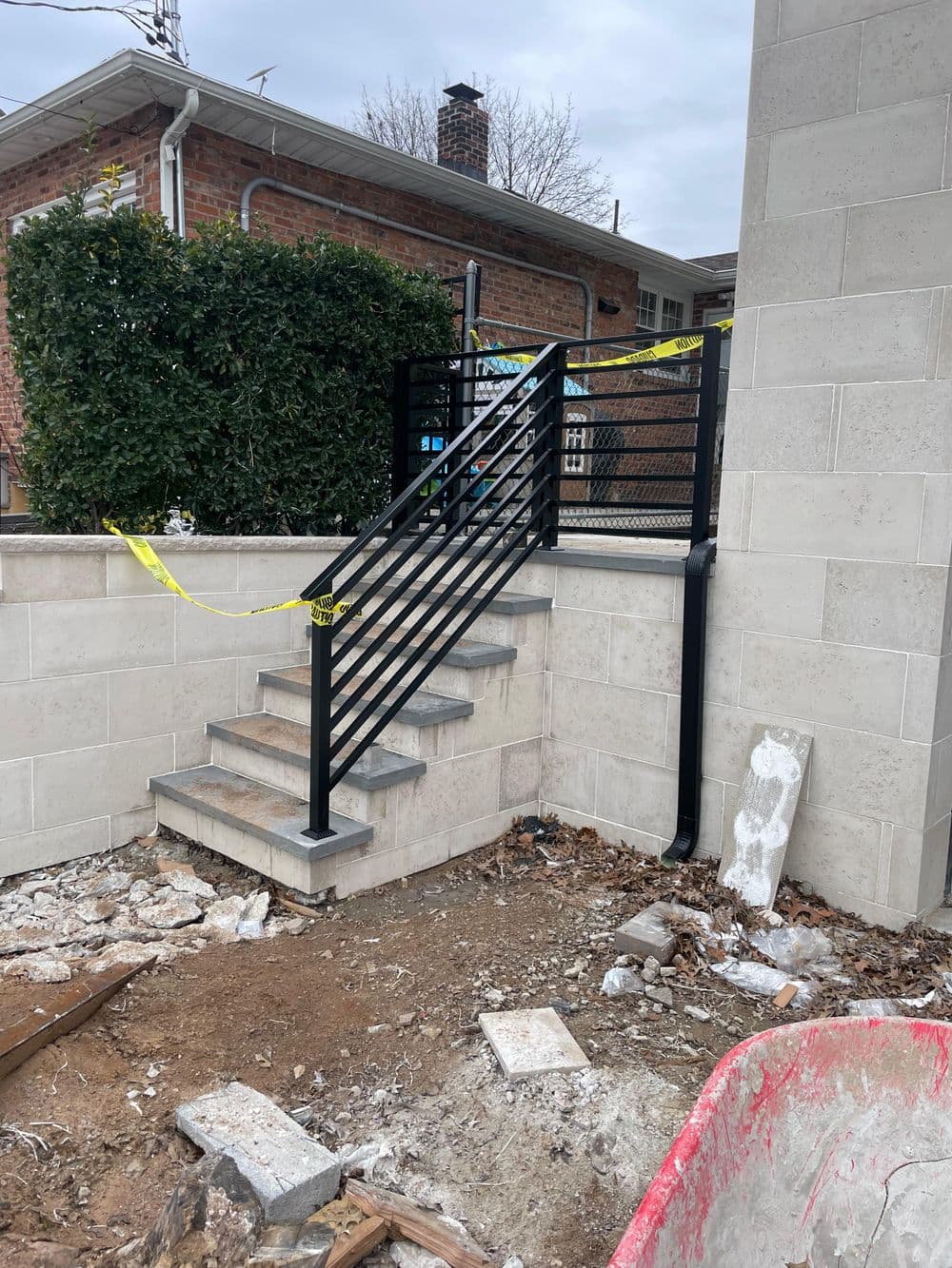 New black metal railing installed on outdoor stairs with construction debris nearby.