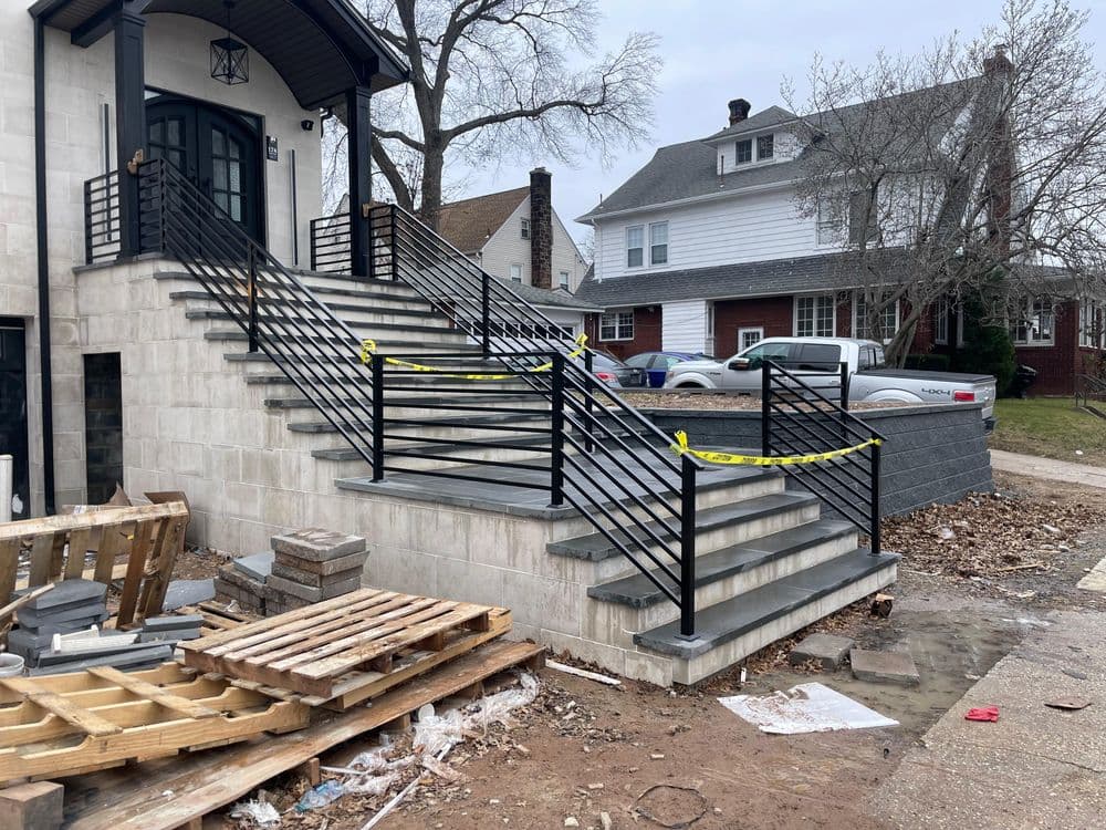 Modern concrete staircase with black railings, under construction, surrounded by materials.