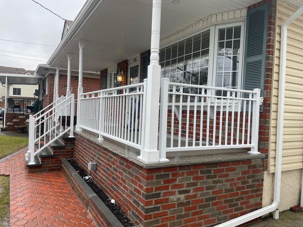 White vinyl railing on a brick porch with concrete steps, enhancing home curb appeal.