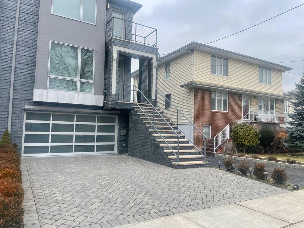 Modern two-story home with stairs and driveway, featuring neutral colors and stylish architecture.