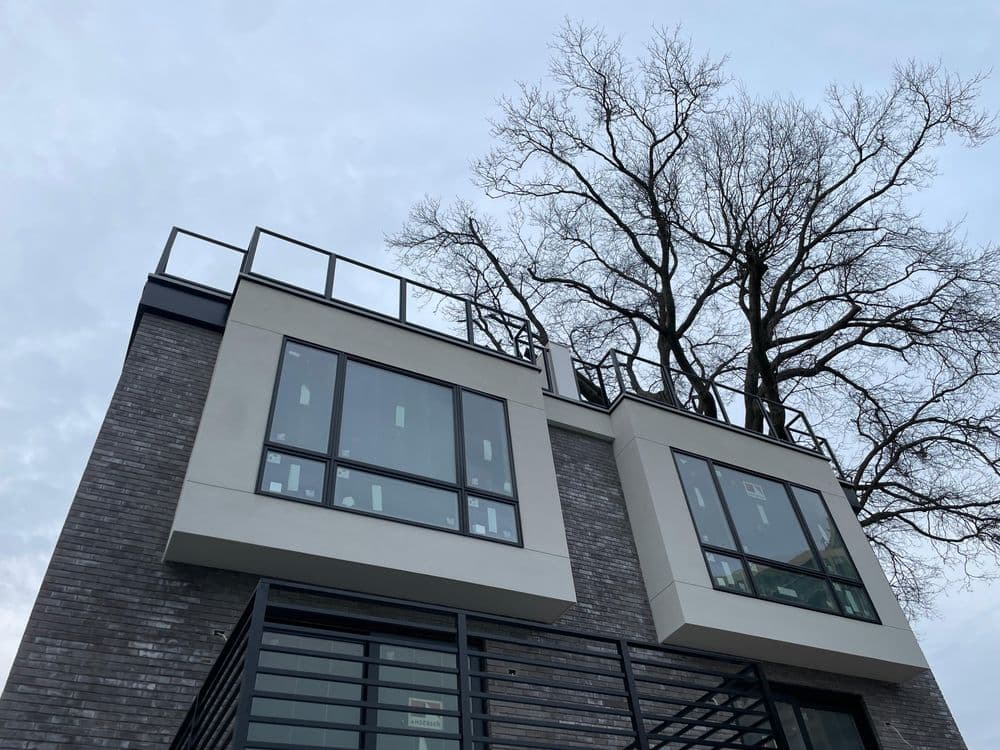 Modern two-story building with large glass windows and a bare tree nearby.