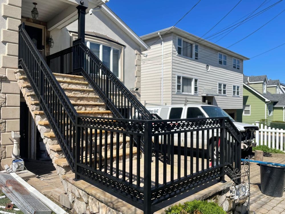 Black wrought iron railings on a stone staircase leading to a residential entryway.