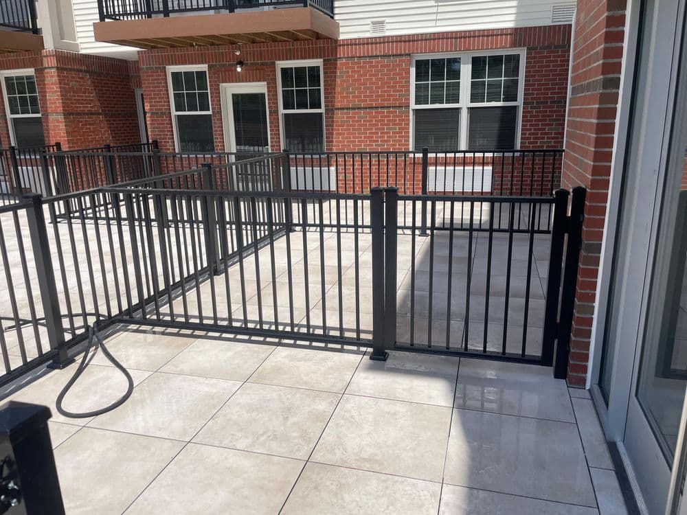 Modern patio with black metal fencing and tiled flooring, showcasing a vibrant outdoor space.