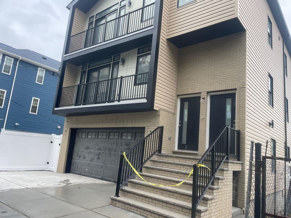 Modern multi-story building with balconies and garage entrance in urban setting.