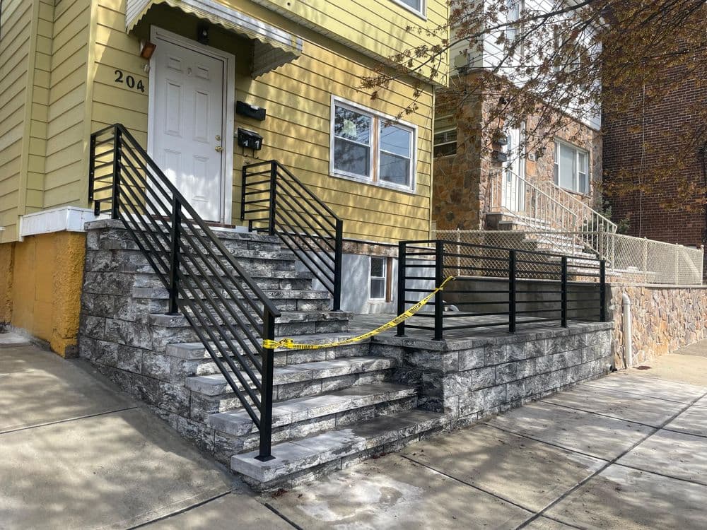 Staircase with black railings and caution tape at a residential building entrance.