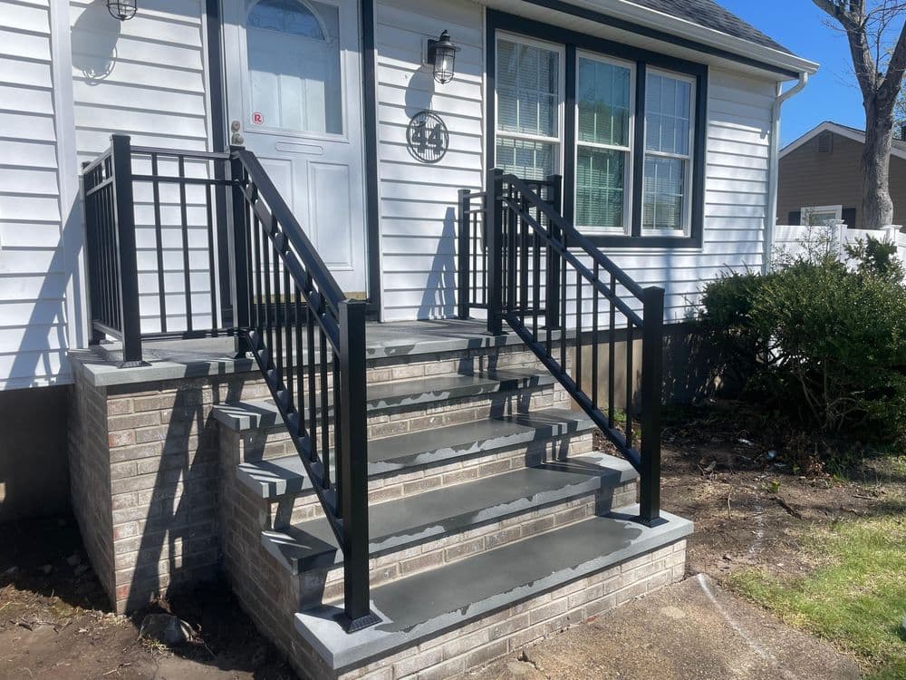 Black metal railings on brick stairs leading to a residential front door.