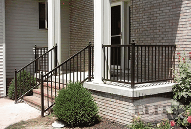 Black metal railings on a brick porch with stairs and greenery, enhancing safety and style.