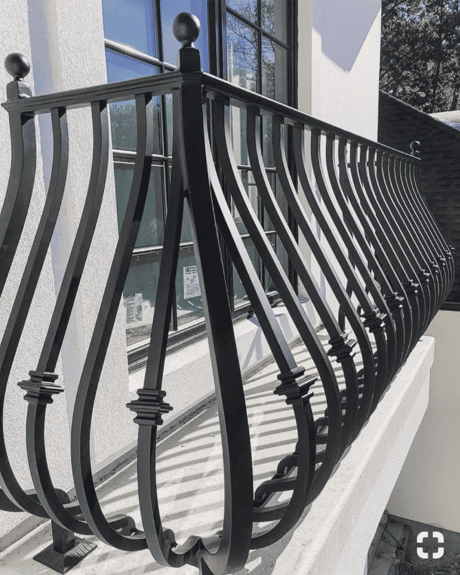 Elegant black wrought iron balcony railing with intricate design and sunlight reflections.