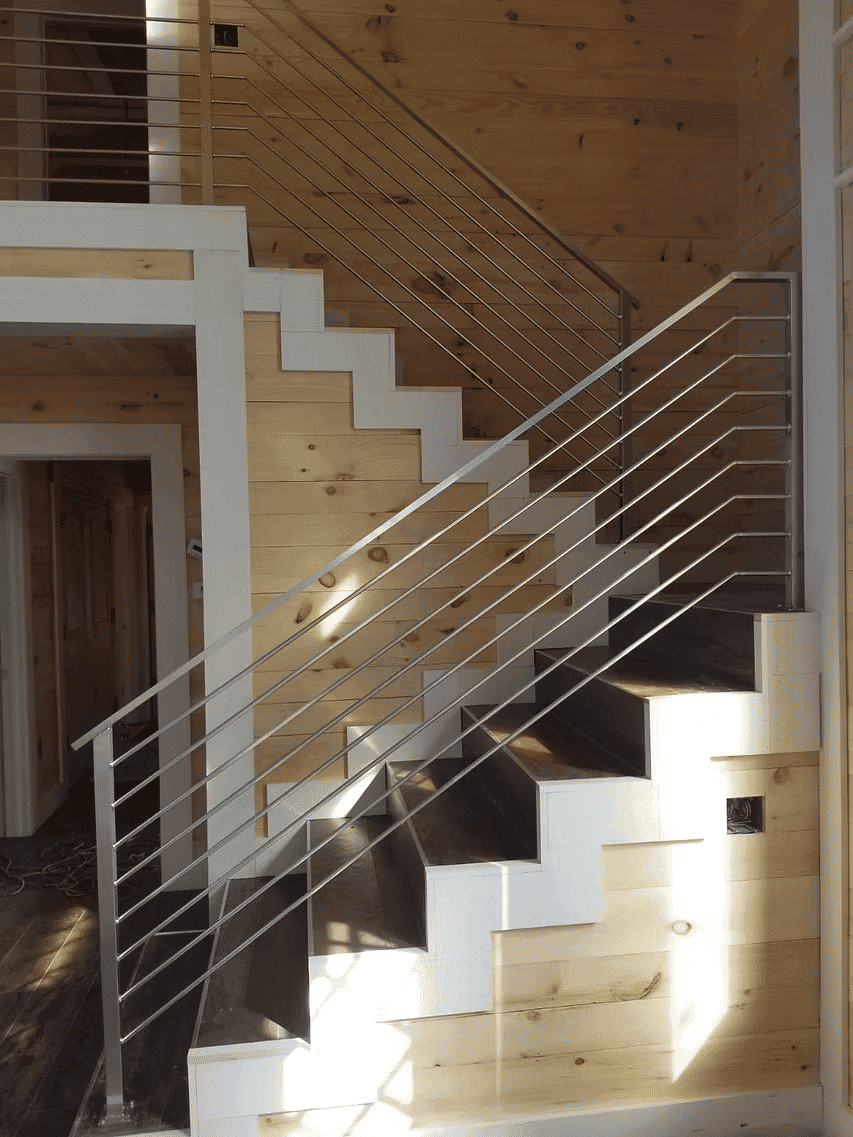 Modern staircase with wooden steps and sleek metal railing in cozy interior setting.