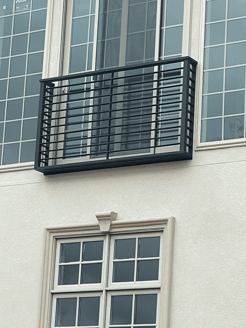 Modern metal balcony railing on a contemporary building facade with large windows.
