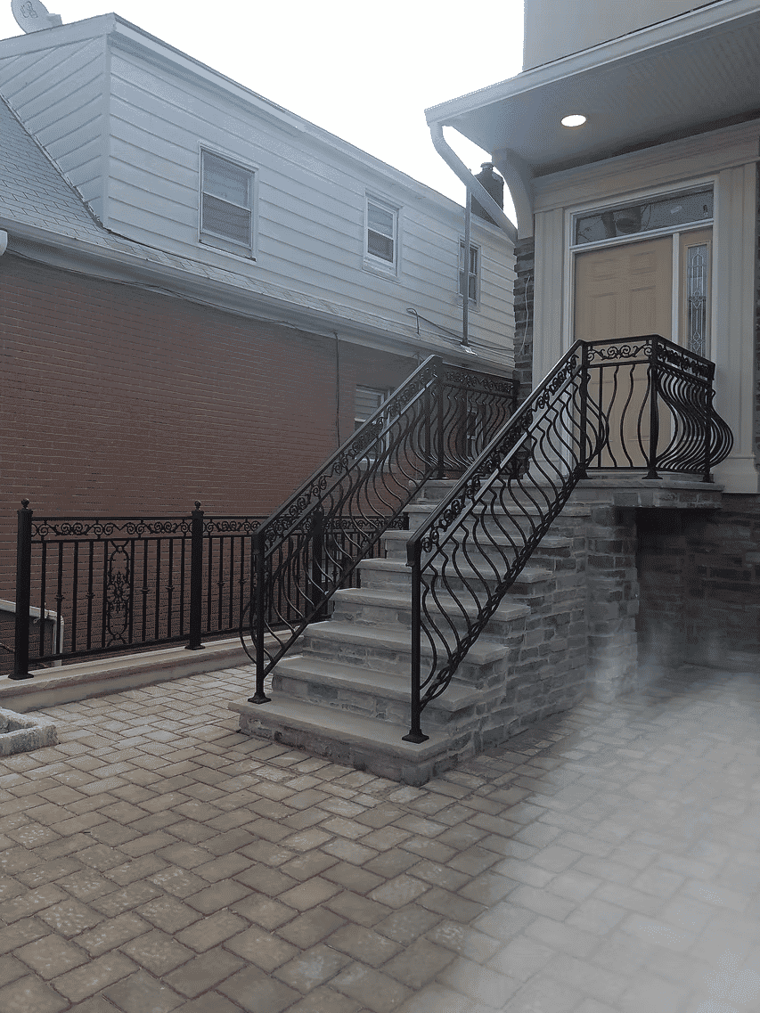 Wrought iron railing and stone steps leading to a house entrance with a decorative doorway.