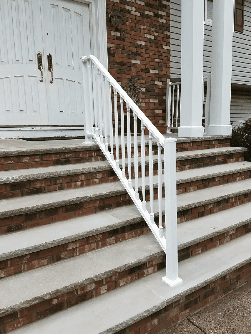 White railing on brick and concrete steps leading to a double door entrance.