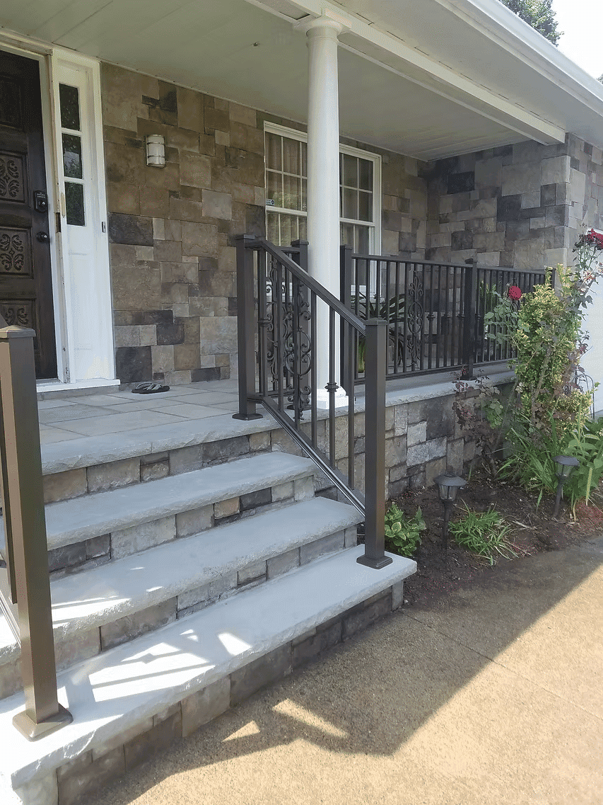 Stone steps leading to a modern home entrance with railing and flower garden.