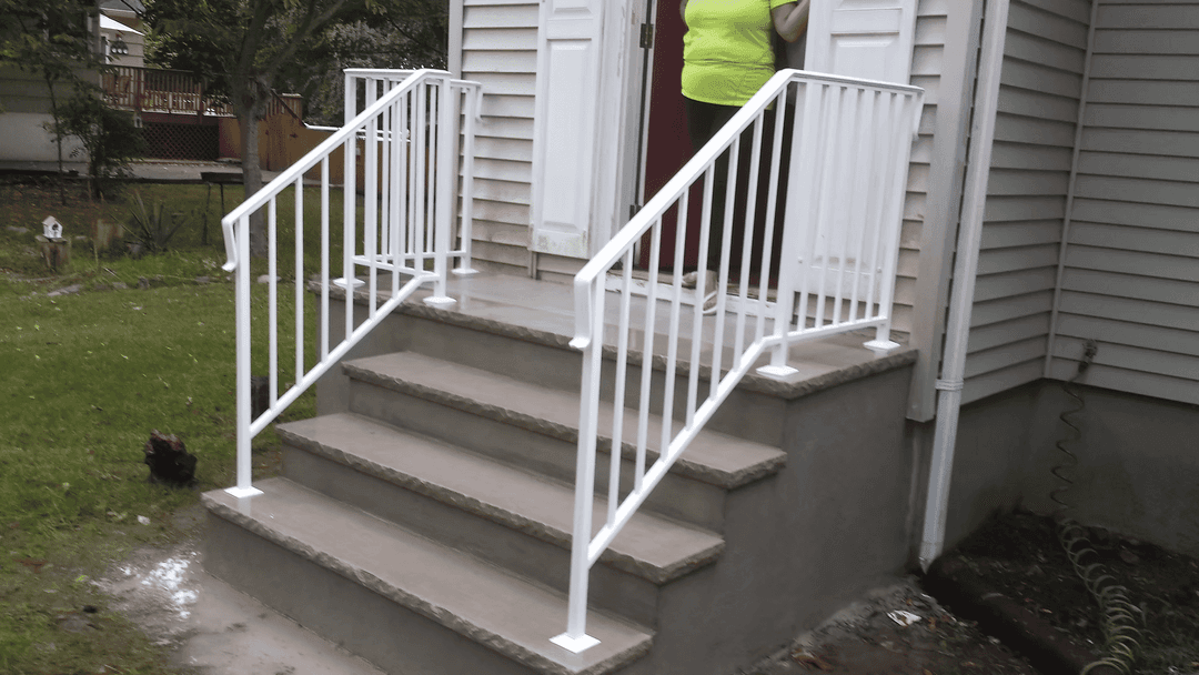 White metal railing on steps leading to a home entrance with a person standing nearby.