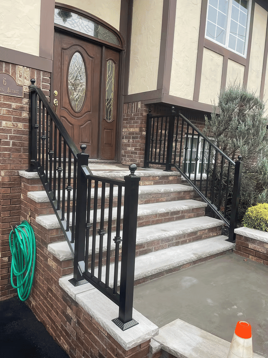 Elegant front entrance with wooden door, brick steps, and black railing in a residential home.