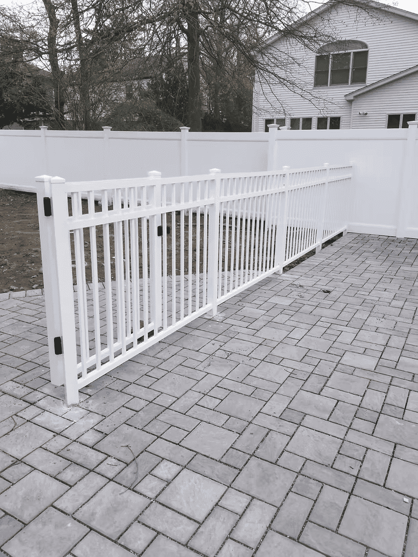 White vinyl fence with black accents enclosing a patio area featuring gray pavers.