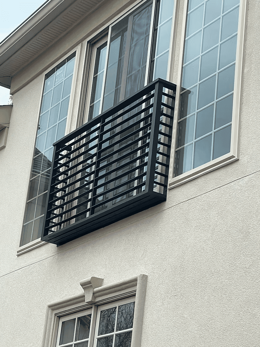 Modern balcony design with black metal railing on a light-colored house exterior.