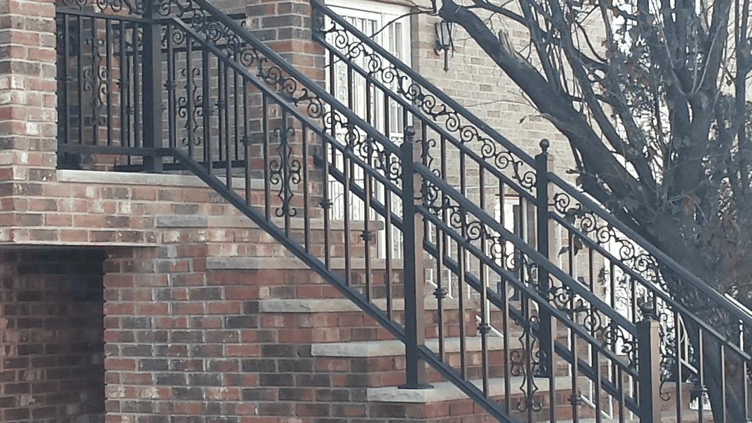 Decorative wrought iron railing on brick staircase, emphasizing elegant design and craftsmanship.