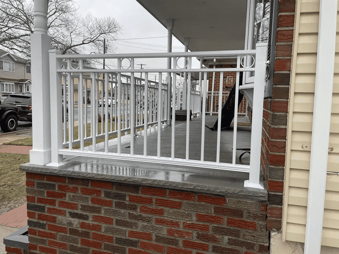 White metal railing on a house porch with brick and concrete details, gray overcast sky.