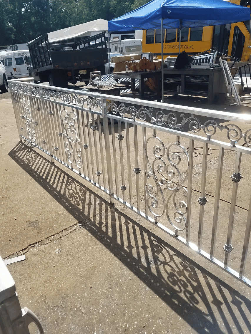 Decorative aluminum fence with intricate scrollwork, showcased outdoors in a sunny setting.