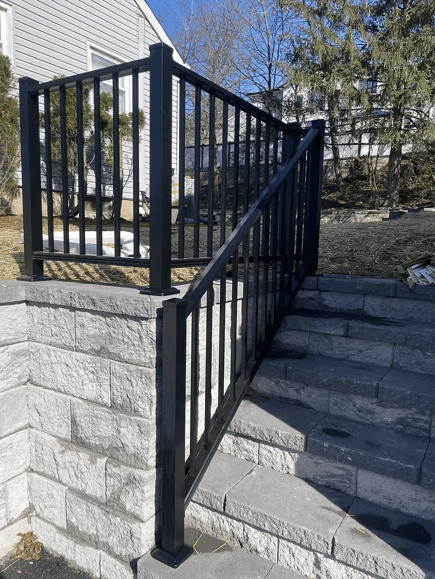 Black metal railing on stone stairs with a landscaped background. Safe and stylish access.