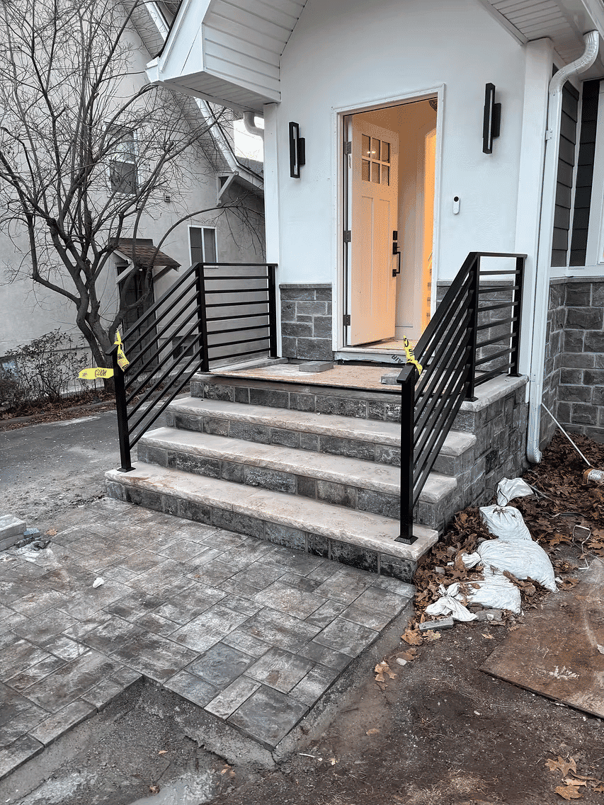 Modern entryway with black railing, stone steps, and a newly renovated porch area.