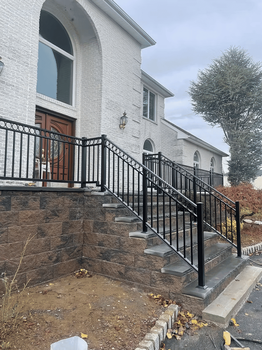 Black railing installed along stone stairs leading to a modern home's entrance.
